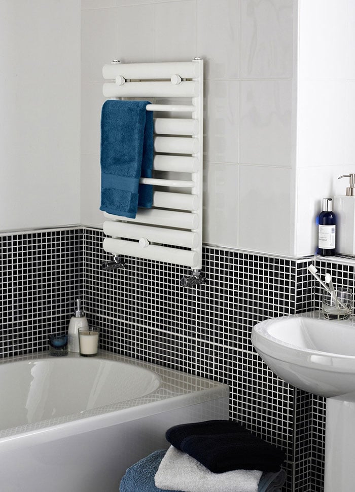 White wall mounted heated towel rail with blue towel- how to warm up your bathroom for winter