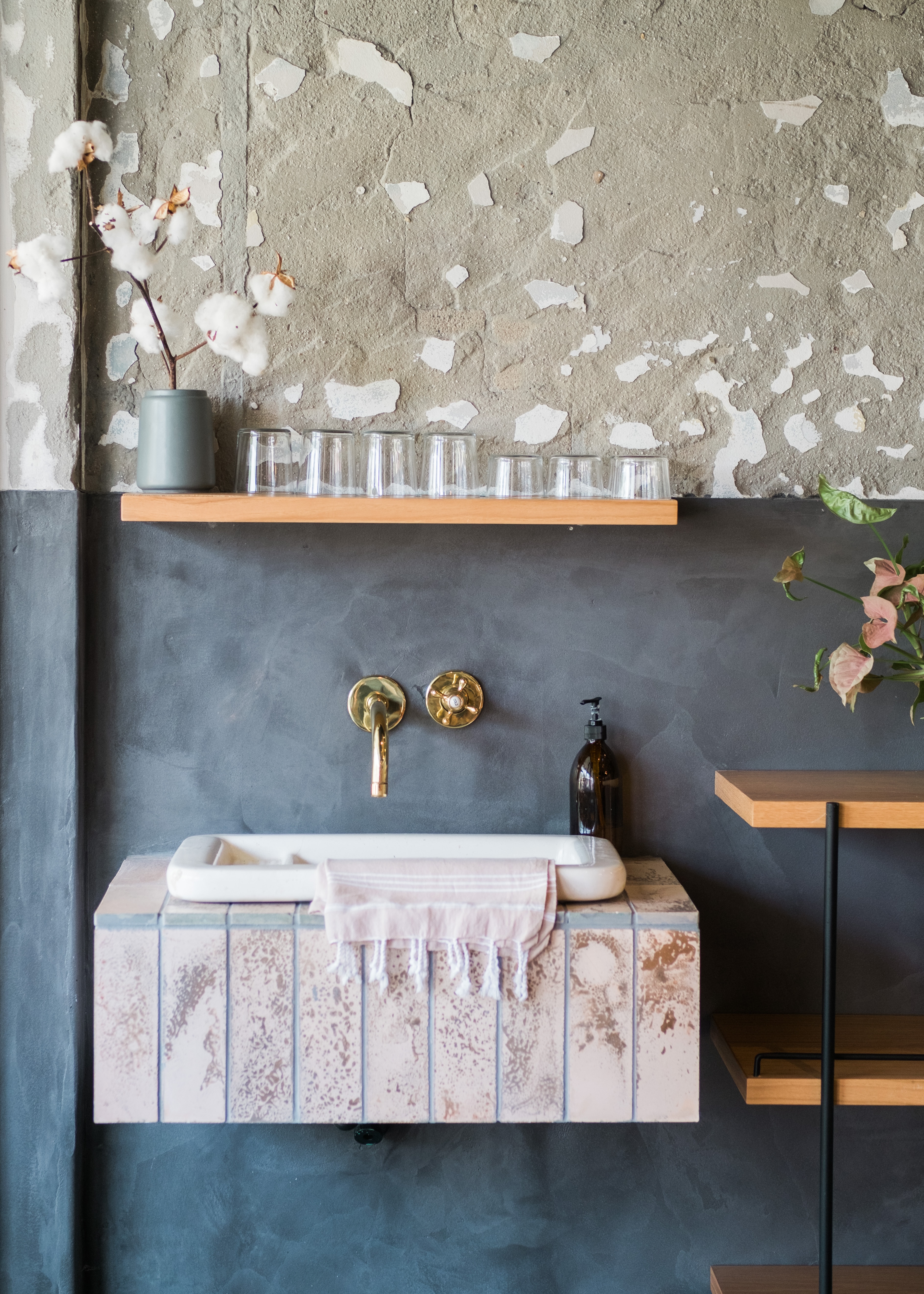 Open wood shelf sitting above a wall-hung basin vanity unit on a concrete bathroom wall