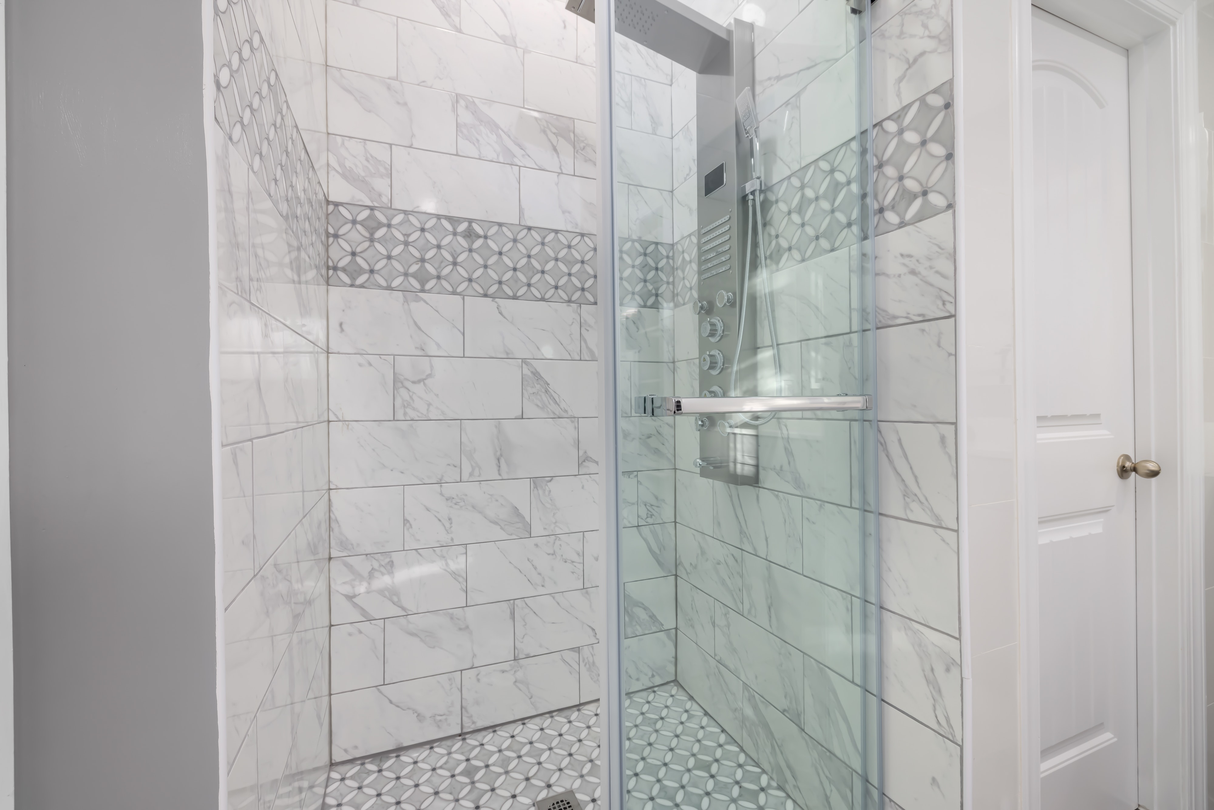 Walk in shower enclosure equipped with a chrome shower column with massaging jets