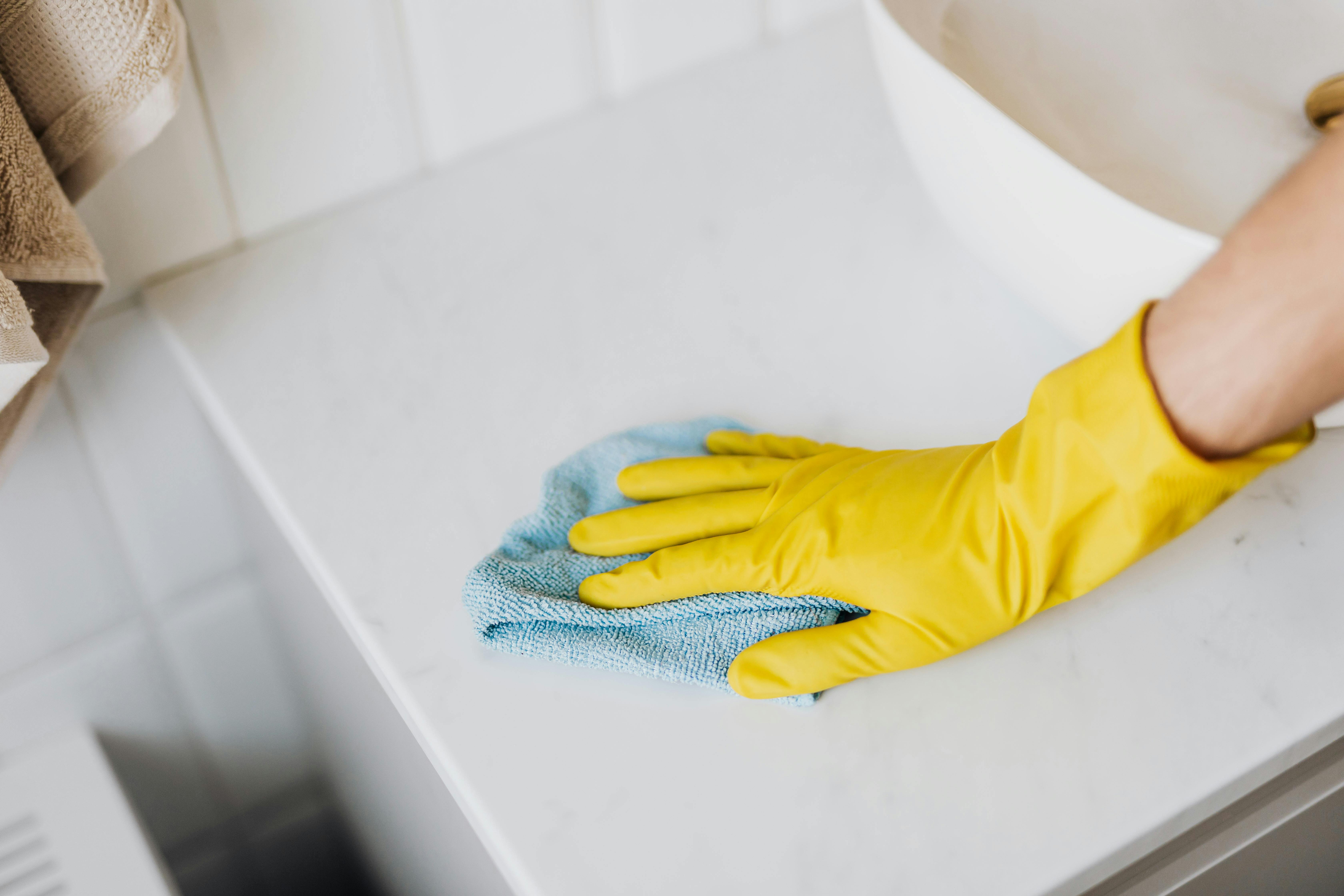 Person wiping a bathroom worktop surface