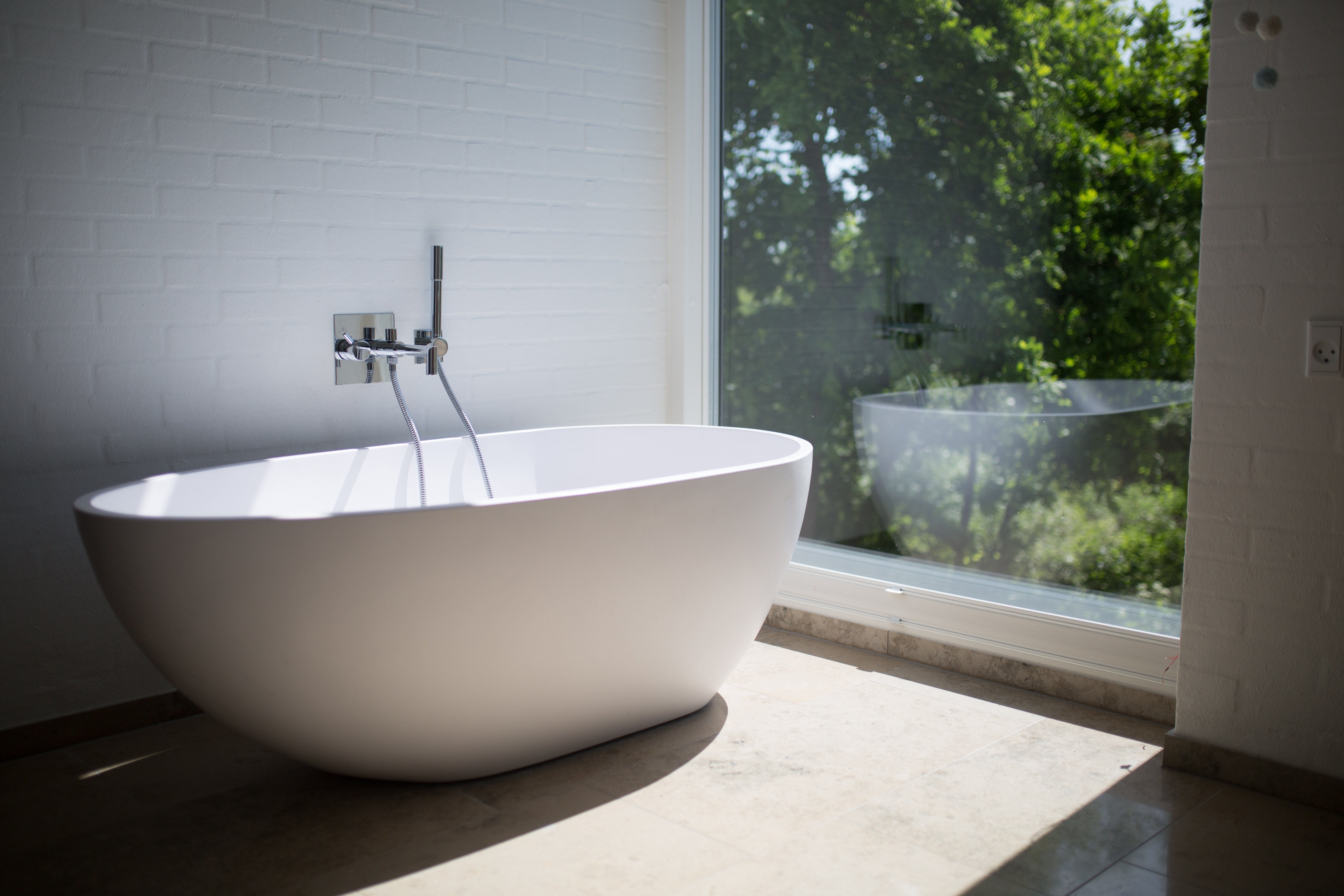 Modern freestanding bathtub next to a ceiling to floor window